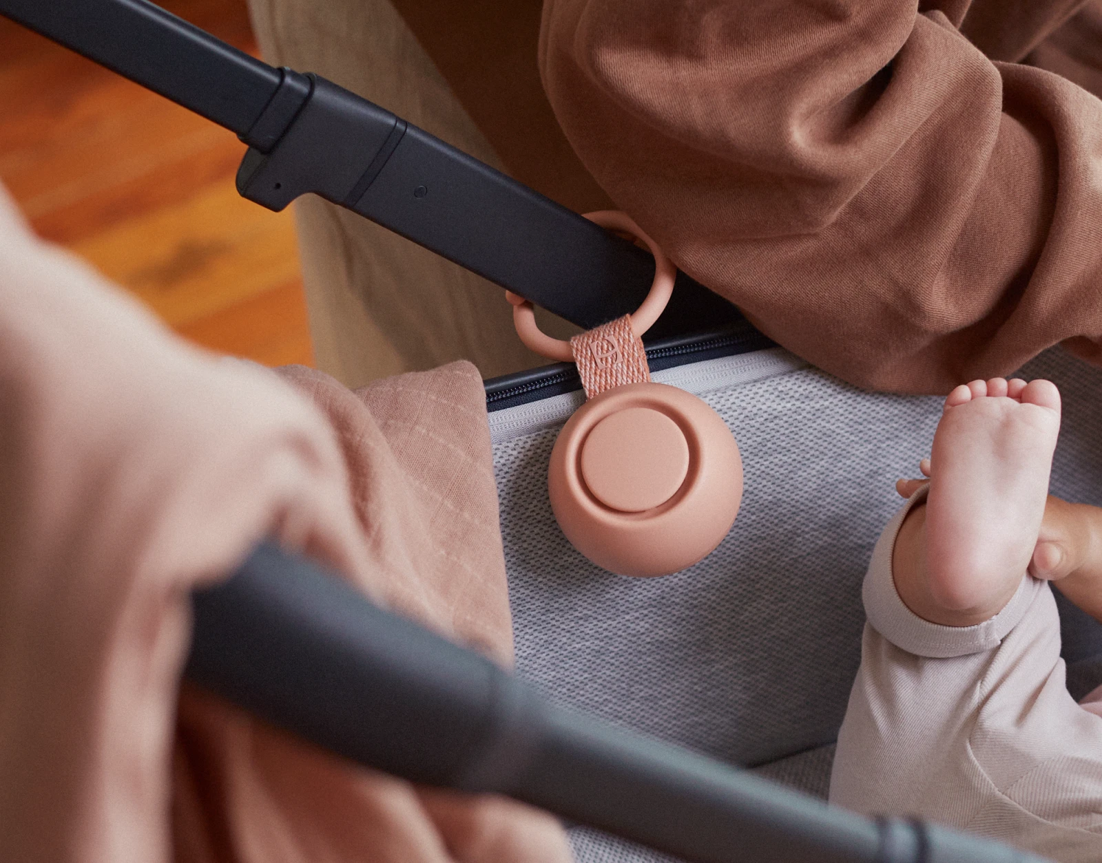 Hatch Go Peach clipped to a stroller while a mother attends her baby in it