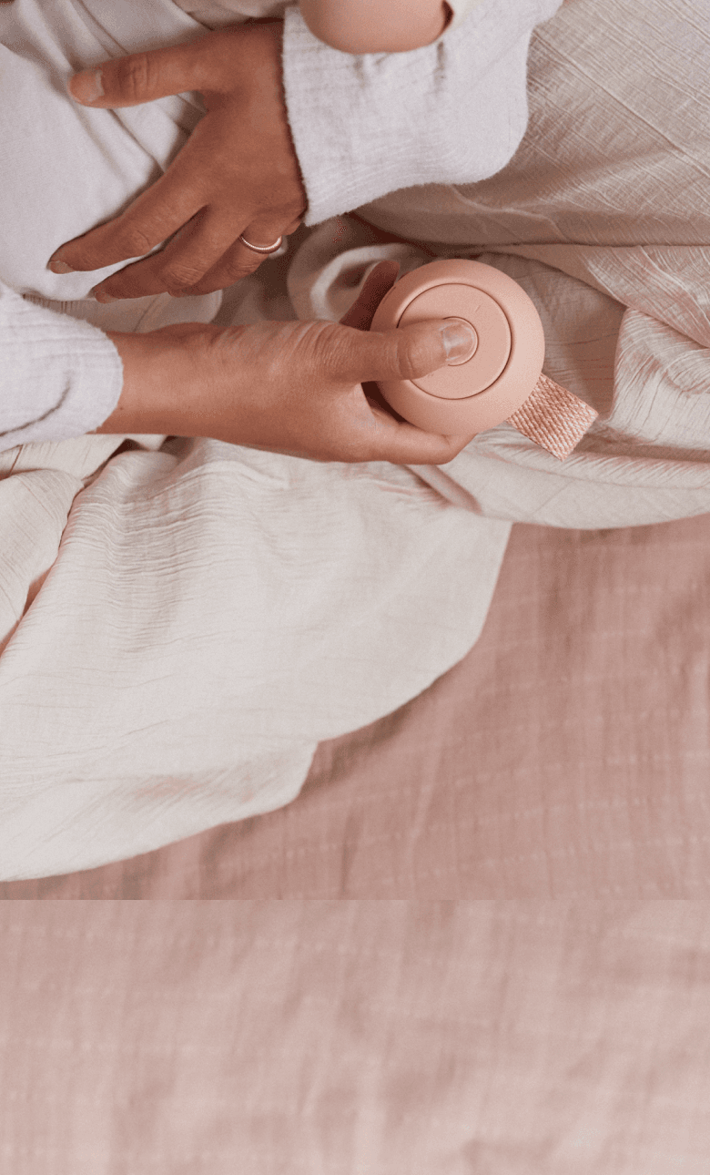 Mother holding baby while pressing button on Hatch peach rest go