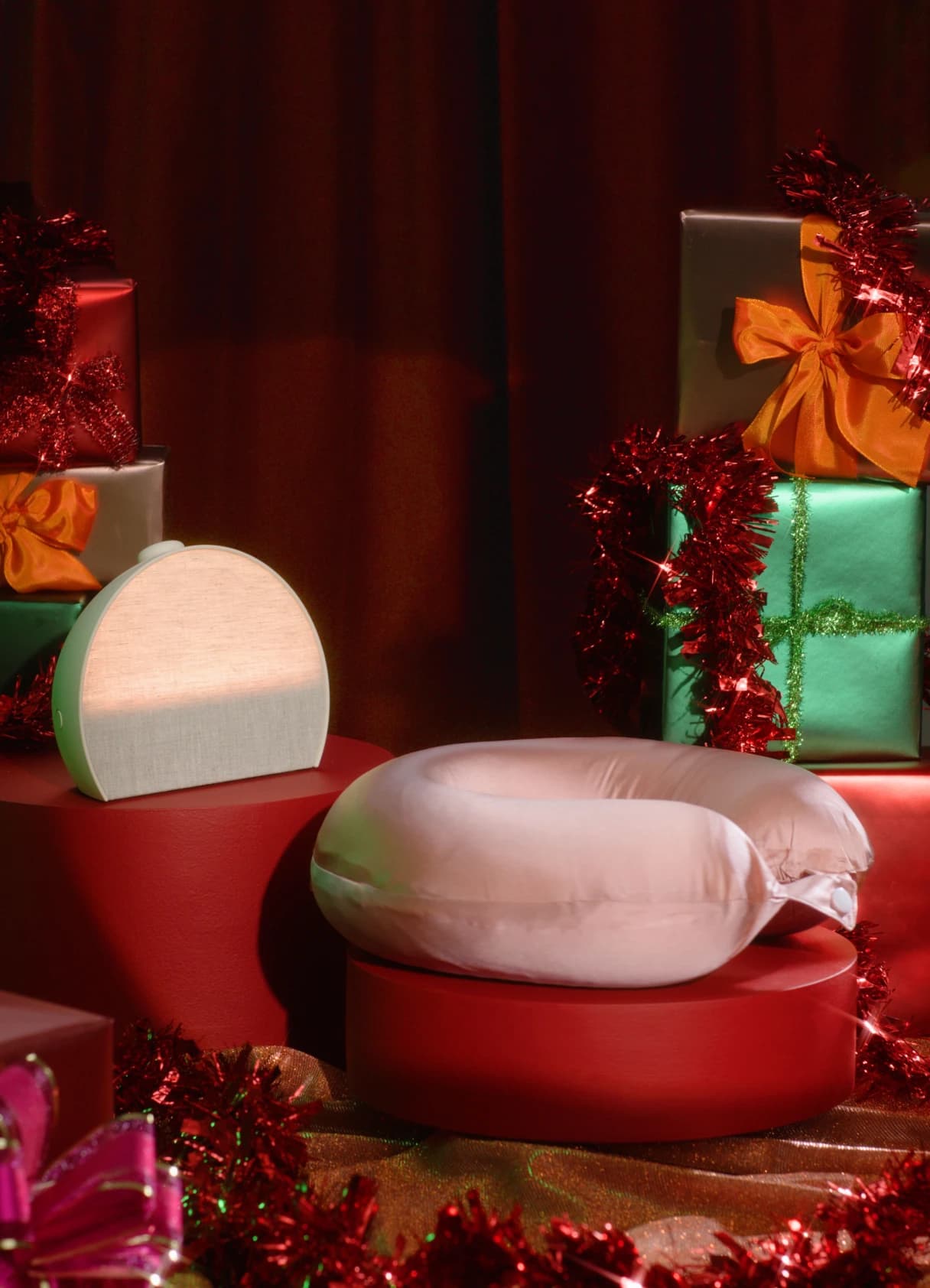 Hatch Restore 3 on a holiday pedestal next to gifts and a travel pillow