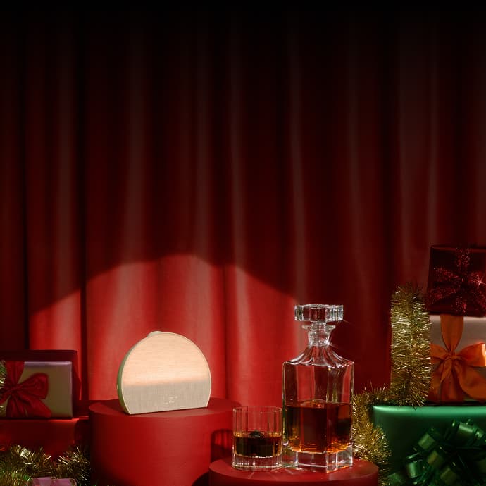 Hatch Restore 3 on a holiday pedestal next to gifts and a whiskey decanter