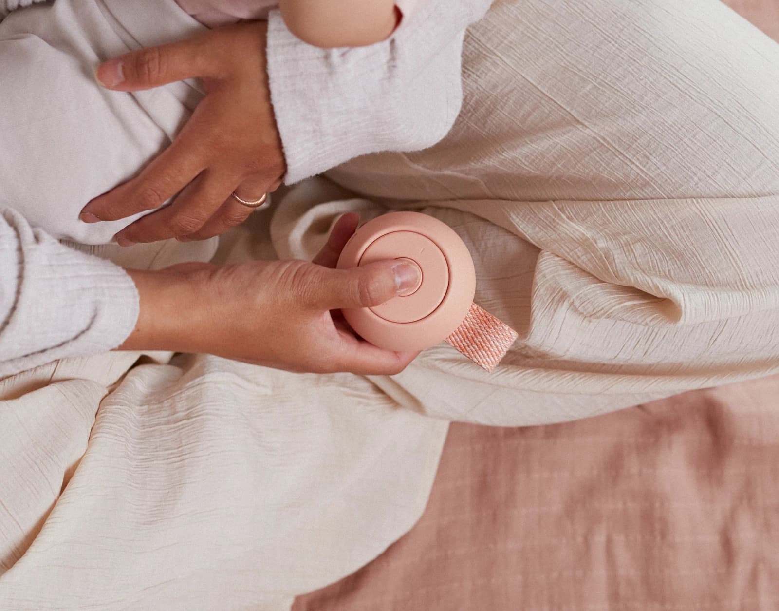 Mother pressing the play button on a Hatch Go Peach while holding a baby