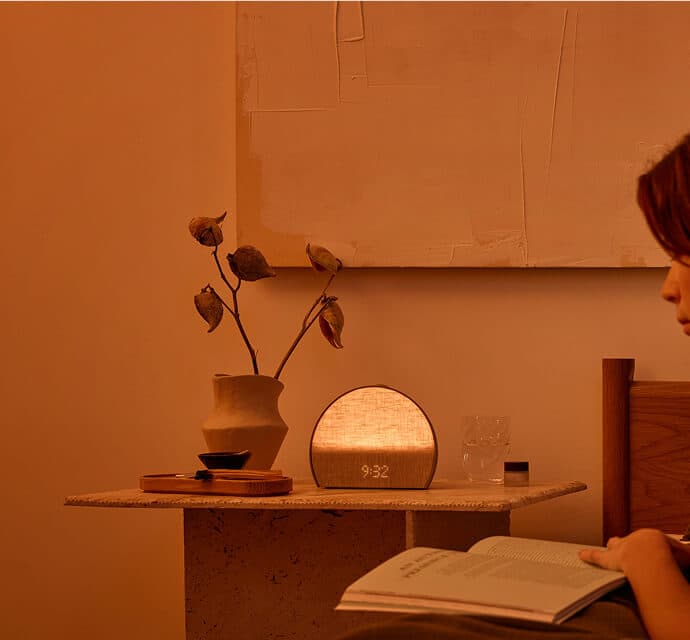 Woman reading book with Restore illuminated on nightstand