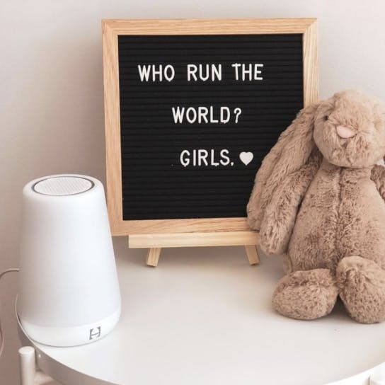 Bedside table with stuffed bunny, rest, and sign that says who run the world? girls.