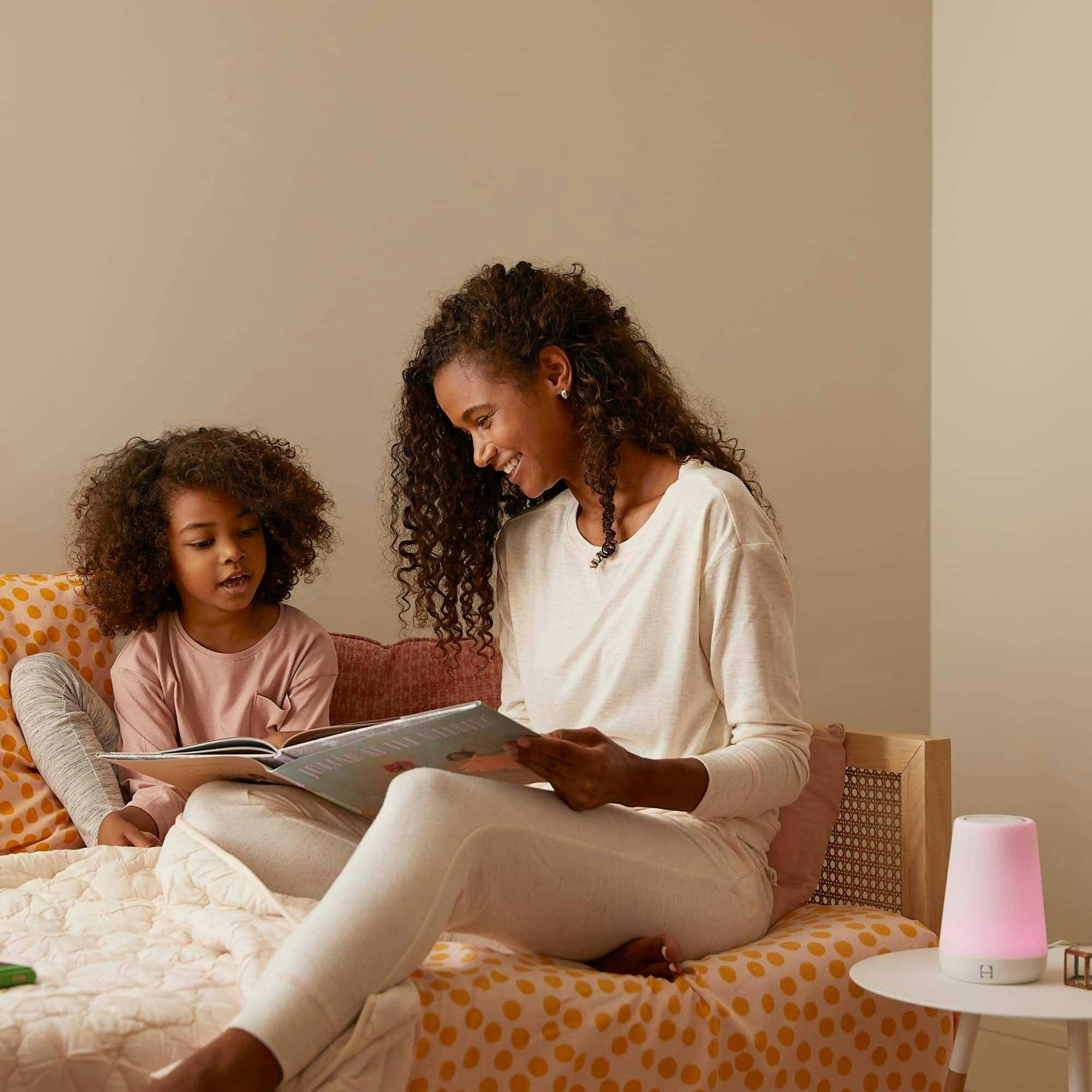 A parent and child read next to illuminated Hatch Rest device