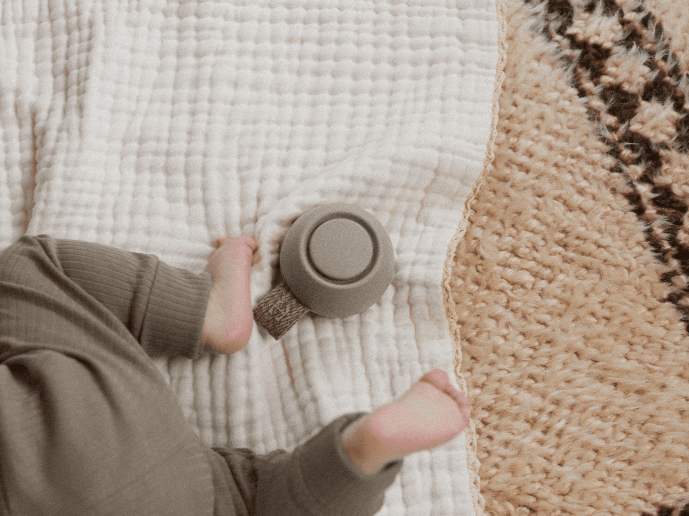 Hatch Go greige colorway sitting next to a baby on a blanket